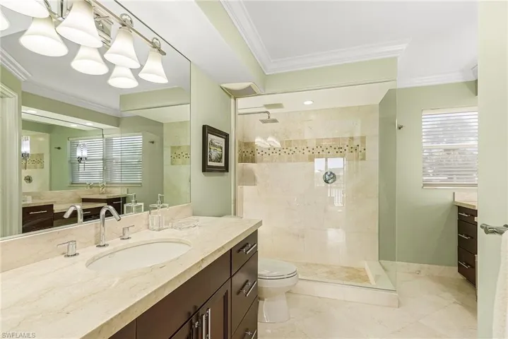 Bathroom with tiled shower, crown molding, and vanity