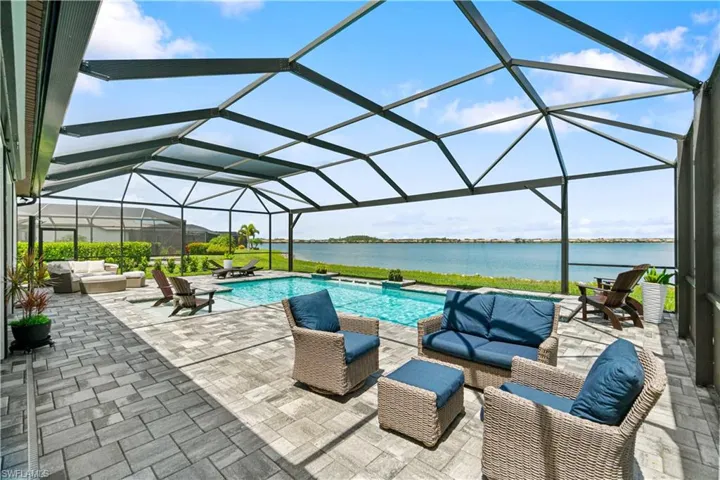 View of swimming pool featuring an outdoor living space, a patio, a water view, and a lanai