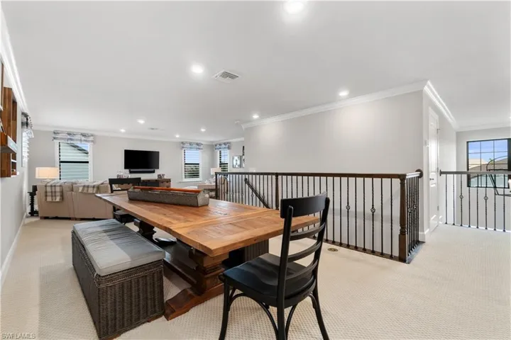Dining area with ornamental molding and light colored carpet