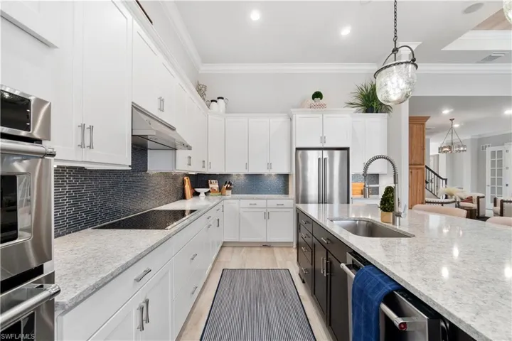Kitchen with sink, appliances with stainless steel finishes, ornamental molding, and backsplash