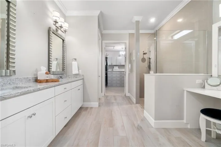Bathroom featuring a shower with shower door, crown molding, hardwood / wood-style floors, and dual bowl vanity