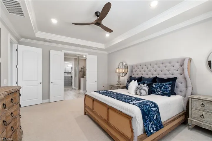 Carpeted bedroom with crown molding, ceiling fan, and a raised ceiling