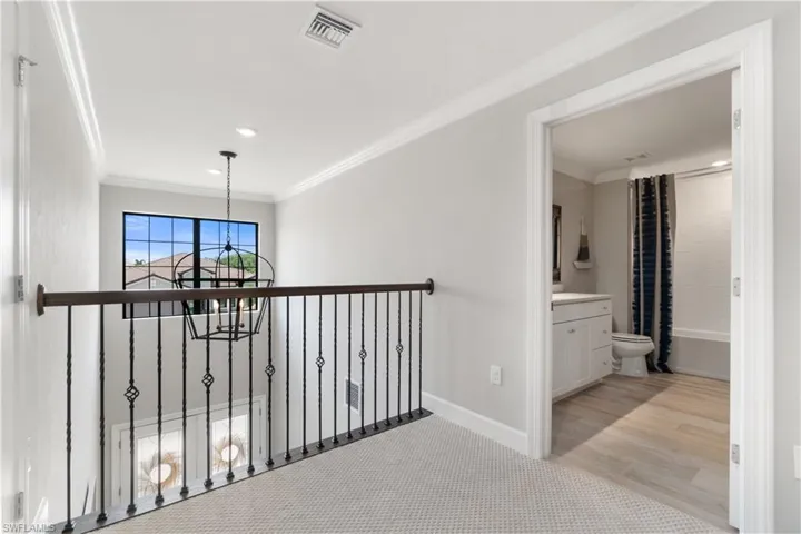 Hall featuring light hardwood / wood-style flooring, crown molding, and a chandelier