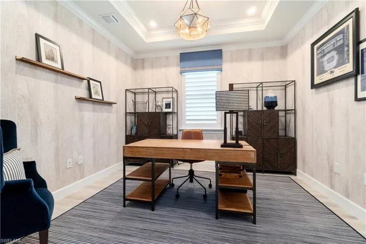 Office area featuring a raised ceiling and crown molding