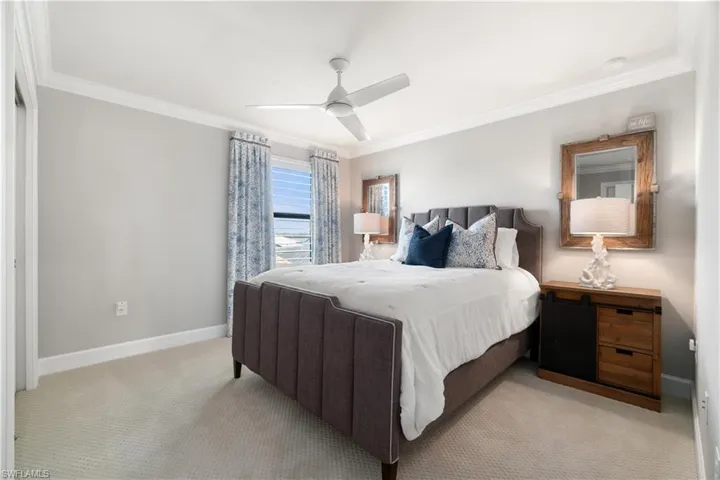 Carpeted bedroom with crown molding and ceiling fan