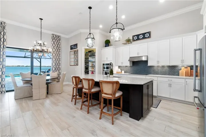 Kitchen featuring white cabinetry, hanging light fixtures, a notable chandelier, and an island with sink