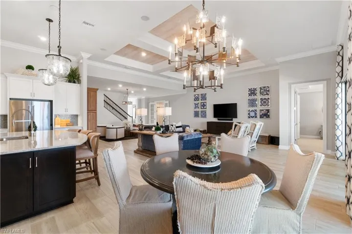 Dining area featuring light wood-type flooring, ornamental molding, an inviting chandelier, beam ceiling, and coffered ceiling