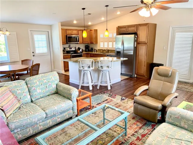 Living area with laminate floors, natural light, lofted ceiling, recessed lighting, and fan