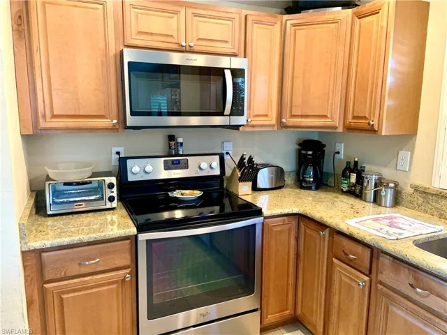 Kitchen with stainless steel, light stone countertops