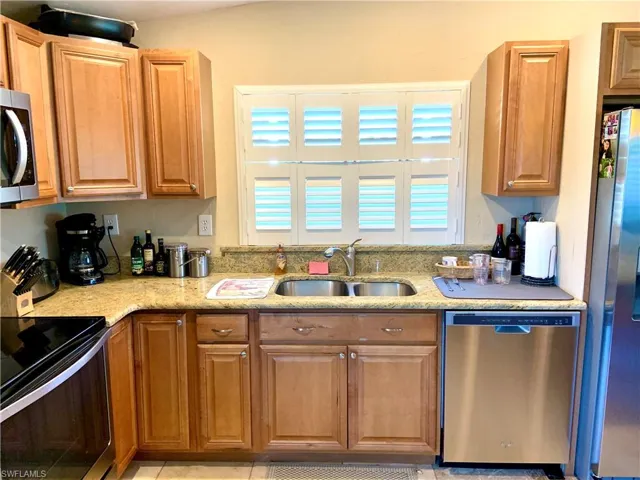 Kitchen with plantation shutters, tile floor, and brown cabinetry