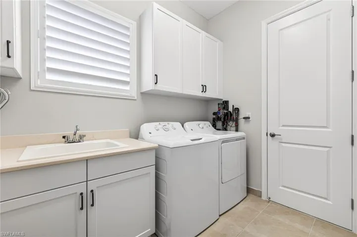 Laundry sink, plantation shutter,  plus lots of cabinetry present in this laundry room!