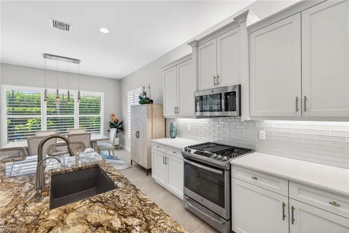 Great view of Blanco sink, updated, gorgeous granite island countertop, and griddle insert in slide-in gas range.
