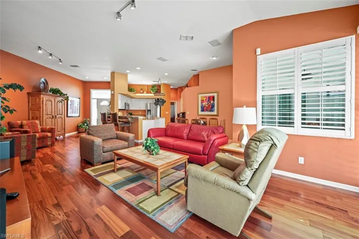 Living room with rail lighting, vaulted ceiling, and hardwood / wood-style flooring