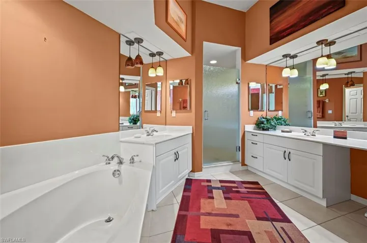 Bathroom with tile patterned flooring, shower with separate bathtub, and vanity