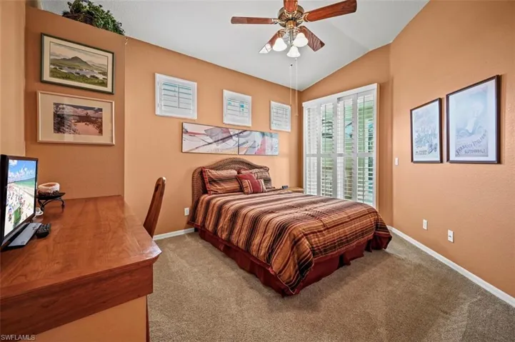 Bedroom with lofted ceiling, ceiling fan, and carpet floors