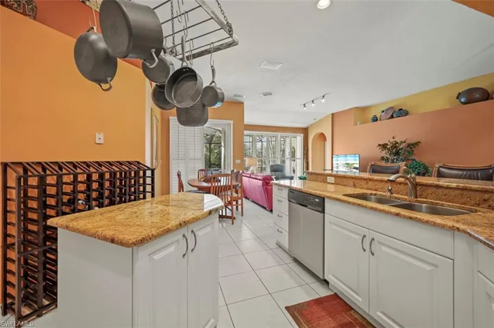 Kitchen featuring dishwasher, light tile patterned floors, sink, light stone counters, and white cabinets