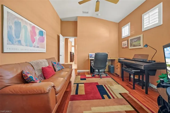Living room featuring vaulted ceiling, wood-type flooring, and ceiling fan