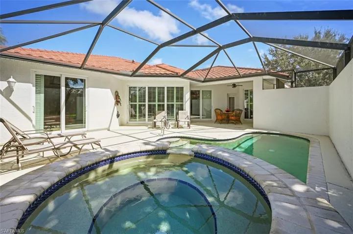View of pool with glass enclosure, a patio area, an in ground hot tub, and ceiling fan