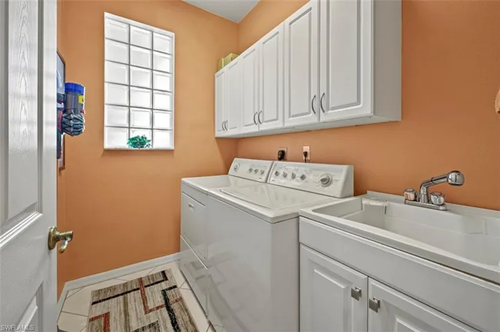 Clothes washing area featuring cabinets, sink, independent washer and dryer, and tile patterned flooring