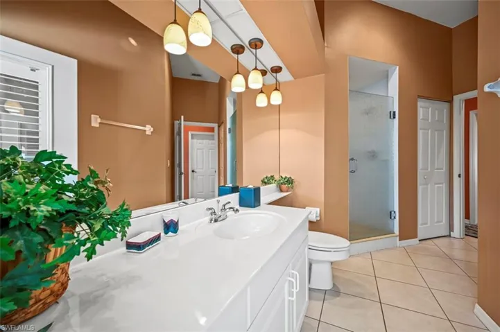 Bathroom featuring vanity, toilet, an enclosed shower, and tile patterned floors