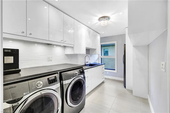 Laundry/Pantry area featuring sink, light tile patterned flooring, cabinets, and washer and dryer and second fridge