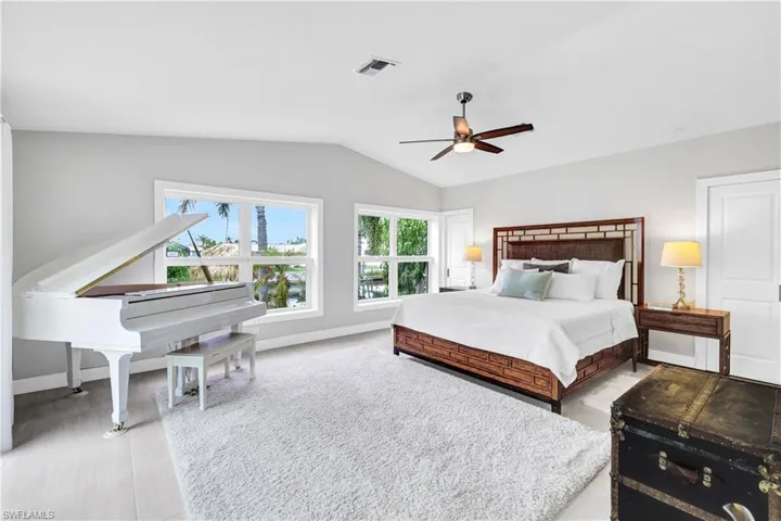 Primary Bedroom featuring lofted ceiling, light tile flooring, Top-down-bottom-up blinds, and ceiling fan