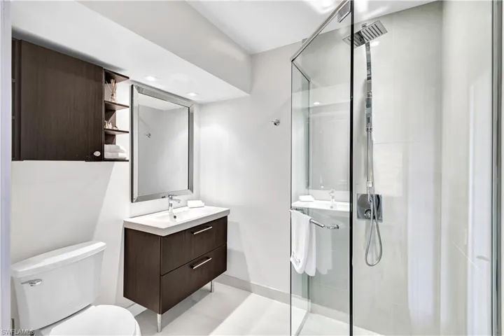 Bathroom featuring vanity, toilet, tile patterned flooring, and an enclosed shower, access to the pool area