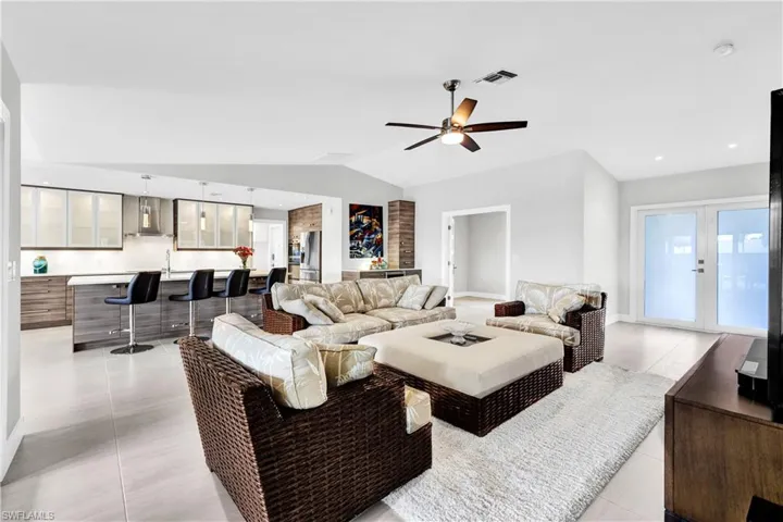 Living room featuring ceiling fan, light tile patterned floors, and vaulted ceiling