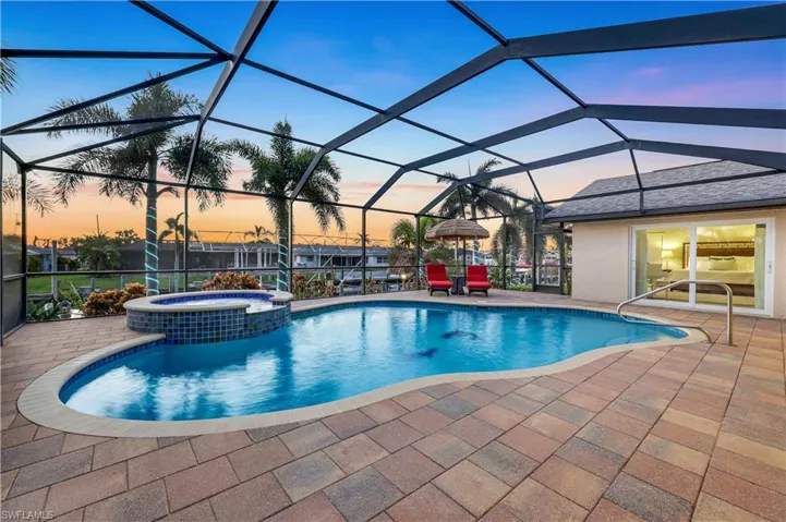 Pool at dusk with an in ground hot tub, a patio area