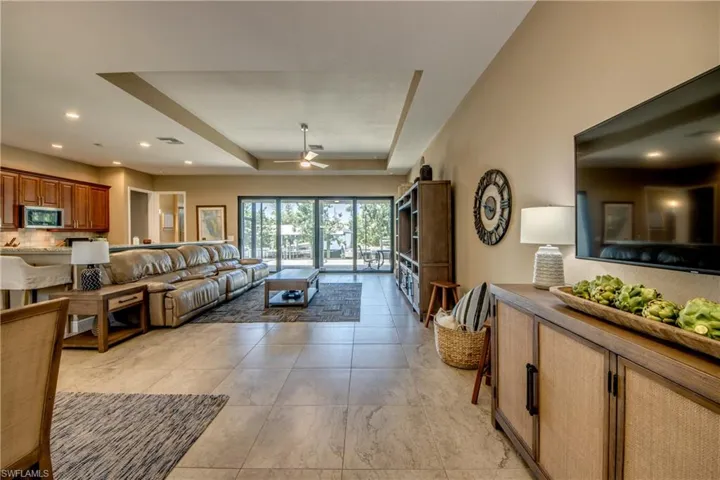 Tiled living room with a tray ceiling and ceiling fan