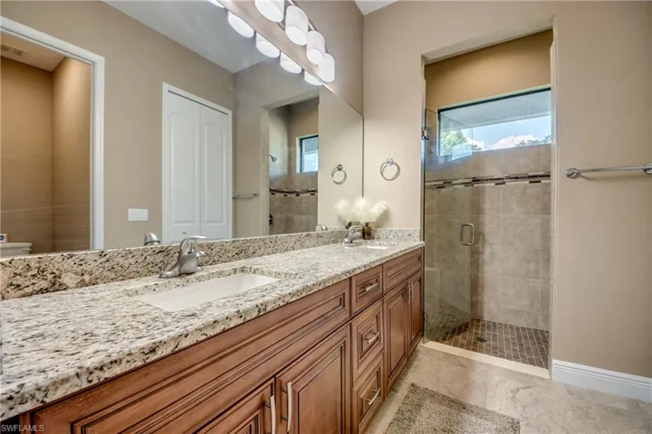Bathroom featuring double sink vanity, walk in shower, toilet, and tile patterned flooring