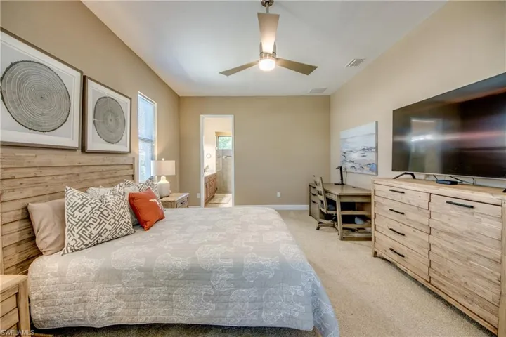 Bedroom featuring light carpet, connected bathroom, and ceiling fan