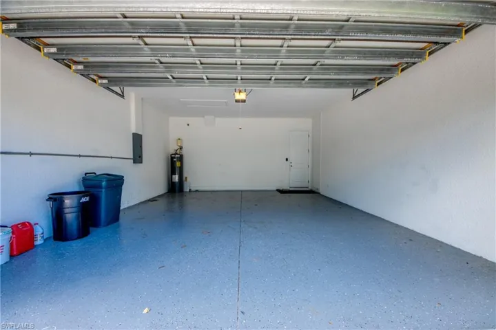 Garage featuring electric water heater, electric panel, and a garage door opener