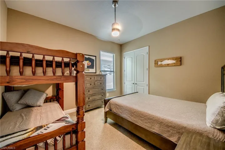 Bedroom with ceiling fan, light colored carpet, and a closet