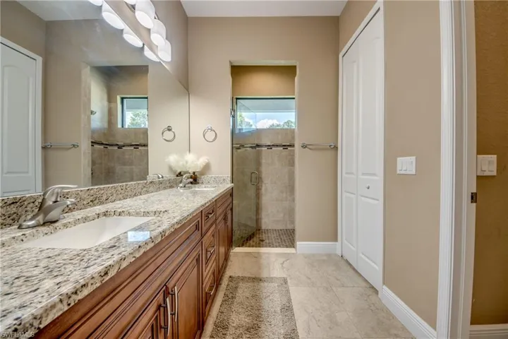 Bathroom with a tile shower, double vanity, and tile patterned floors