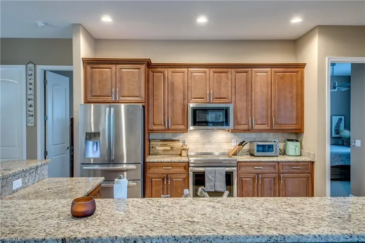 Kitchen with appliances with stainless steel finishes, tasteful backsplash, and light stone countertops