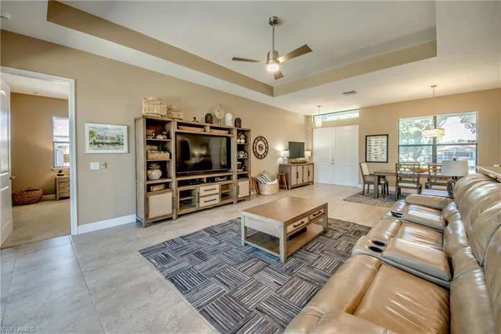 Carpeted living room with a tray ceiling and ceiling fan
