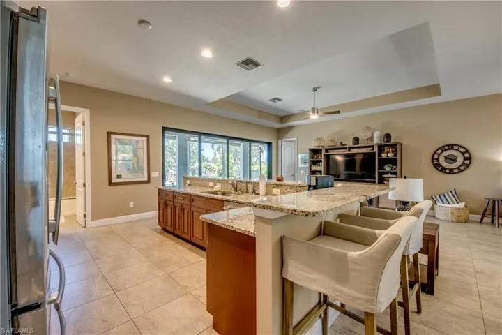 Kitchen featuring appliances with stainless steel finishes, a raised ceiling, light stone counters, and light tile patterned floors
