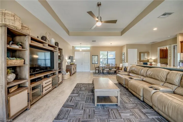 Living room featuring ceiling fan, a raised ceiling, and dark tile patterned floors