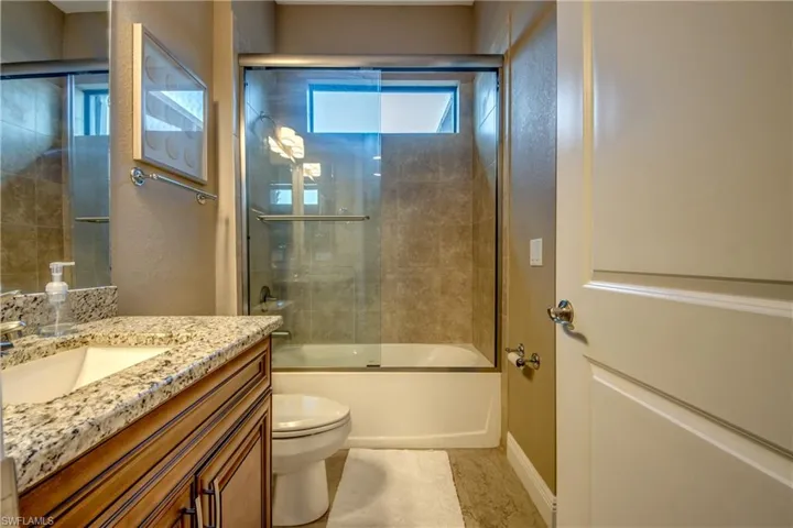 Full bathroom featuring vanity, a wealth of natural light, bath / shower combo with glass door, and toilet