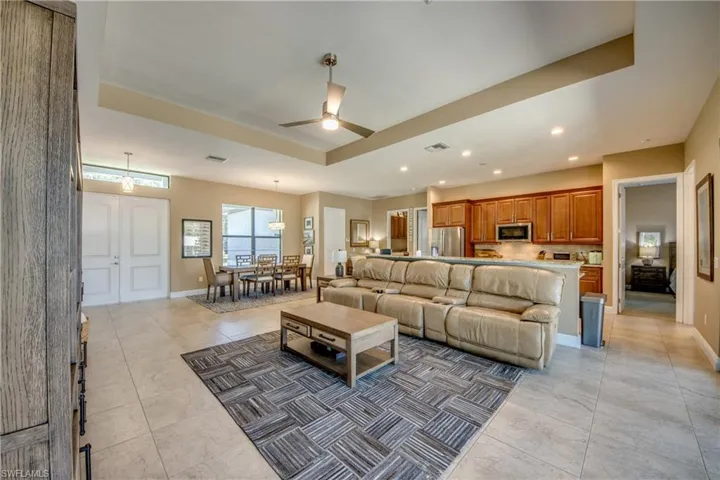 Tiled living room with ceiling fan and a raised ceiling