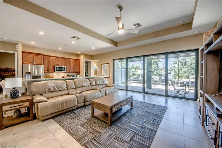 Tiled living room featuring ceiling fan and a raised ceiling