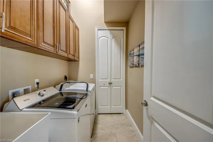 Laundry area with cabinets, light tile patterned floors, sink, and washer and dryer
