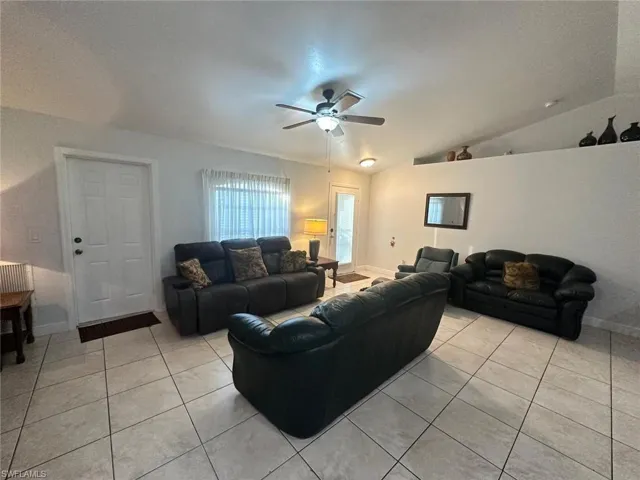 Tiled living room with ceiling fan and lofted ceiling