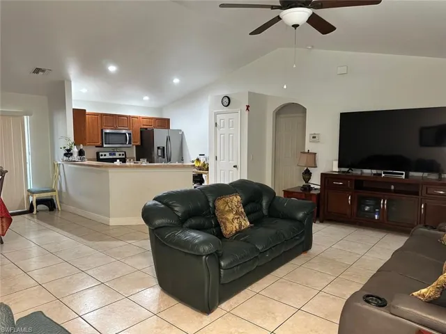 Living room featuring ceiling fan, lofted ceiling, and light tile patterned floors