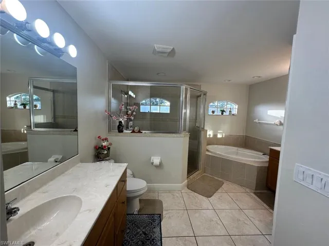 Primary bathroom with vanity, toilet, separate shower and tub, and tile patterned flooring
