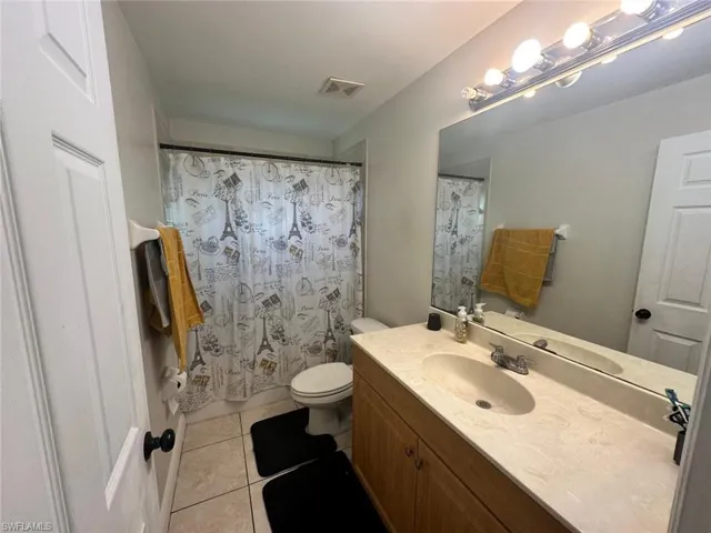 Bathroom featuring vanity, a shower with curtain, tile patterned floors, and toilet