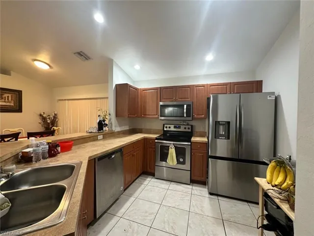 Kitchen with stainless steel appliances, kitchen peninsula, sink, and light tile patterned floors