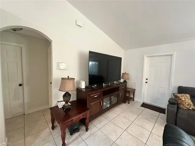 Living room with vaulted ceiling and light tile patterned floors