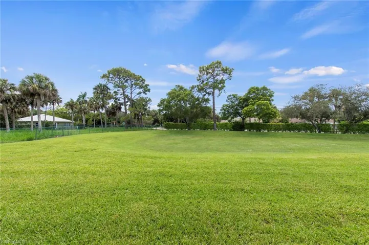 Expansive green lawn with mature trees and perimeter fencing